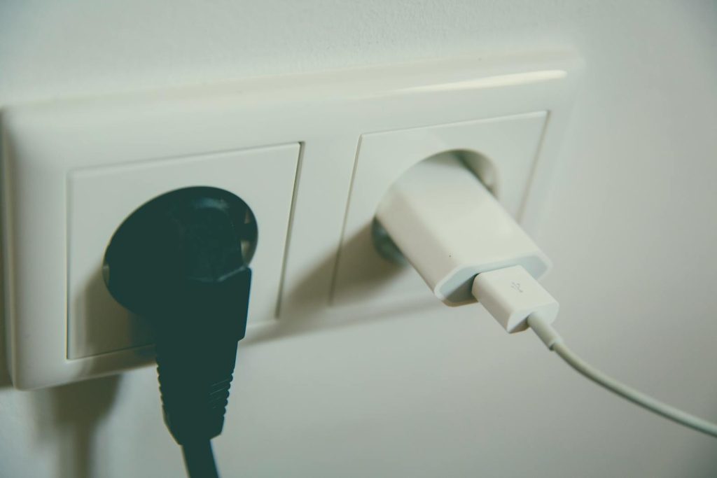 A close-up view of a wall outlet with two plugs inserted, capturing the simplicity of electrical connectivity. Ekstra stikkontakt