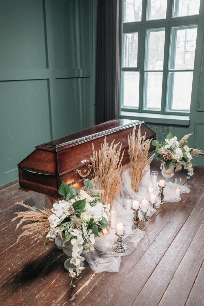 A serene indoor funeral setting featuring a wooden coffin, candles, and delicate floral decorations.begravelseskostnader, begravelse pris