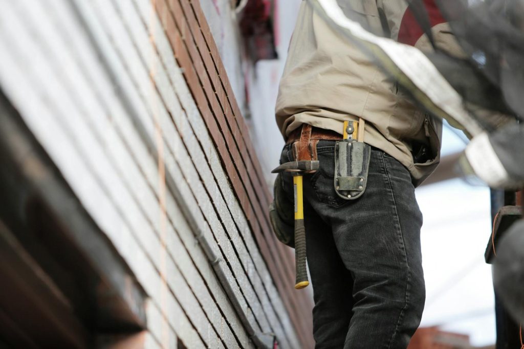 Close-up of a construction worker with hammer and tools, focused on the job. snekker, snekkerpriser, pris for snekker, snekker timepris, hva koster en snekker