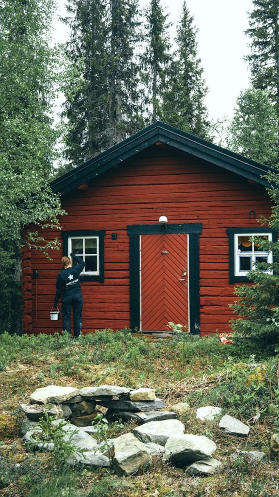 man in black jacket standing beside brown wooden house during daytime, maler pris, utvending, innvendig