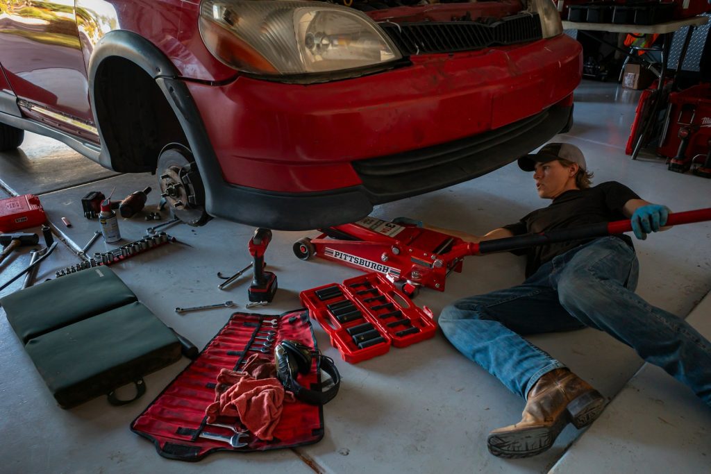 a man working on a car in a garage, bilverkstedpriser