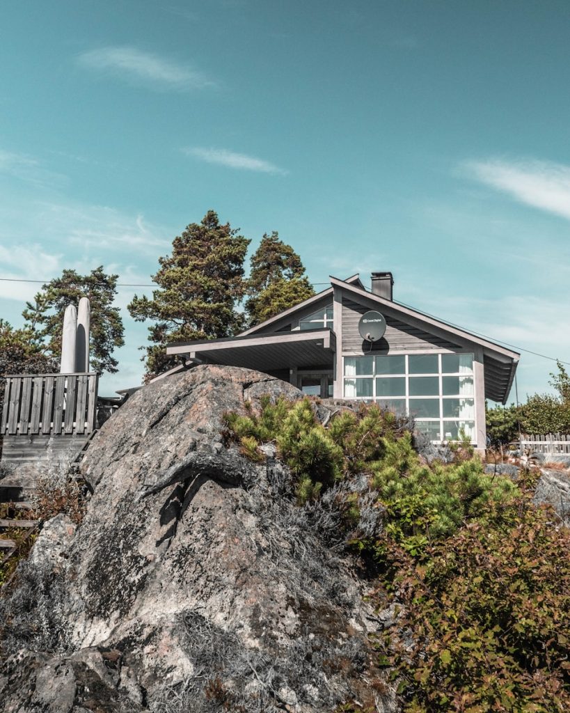 white wooden house near green trees under blue sky during daytime, leie hytte eller airbnb, priser