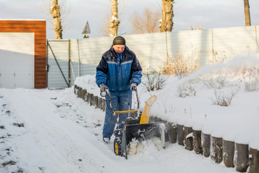 a man shoveling snow with a snow blower, snømåking priser