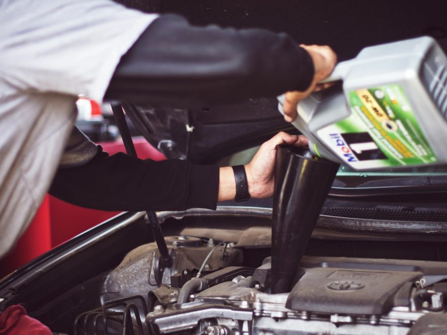 man refilling motor oil on car engine bay, eu kontroll