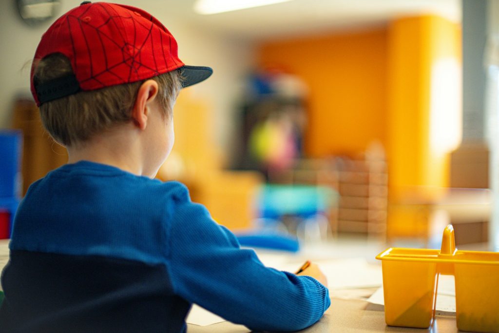 a young boy sitting at a table writing on a piece of paper, barnehage, priser