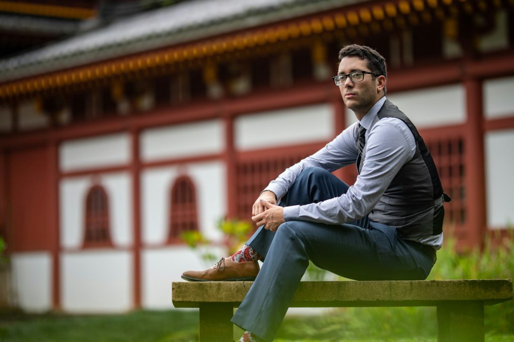 a man sitting on a bench in front of a building, begravelseskostnader, begravelse pris